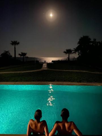 阿依纳帕Ionion Beachfront Villa的两人晚上坐在游泳池旁边