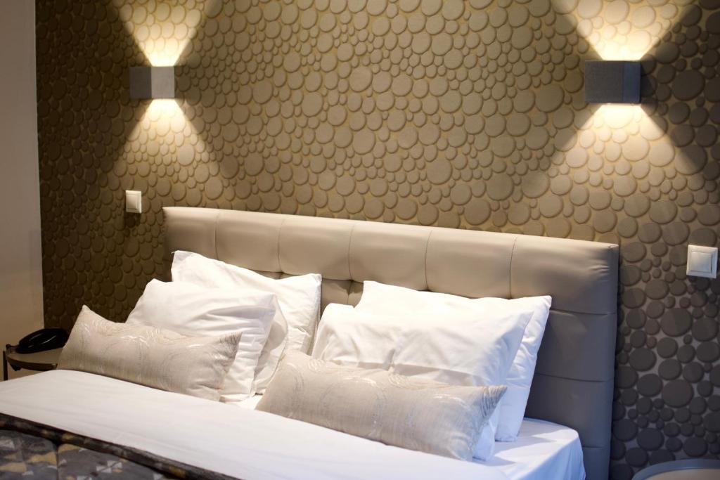 雅典雅典弥诺阿酒店的一间卧室配有带白色枕头和灯的床。
