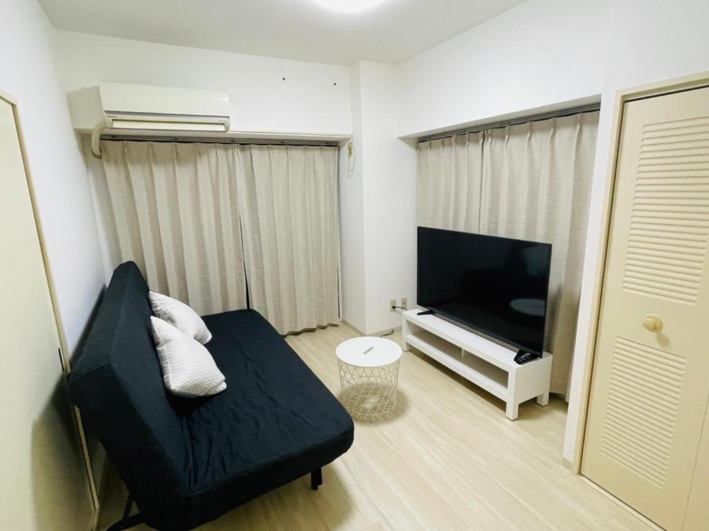 KusugaurachōASUKA HINODECHO ｌ日の出町的客厅配有黑色沙发和平面电视。