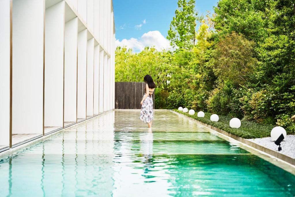 佐贺市Garden Terrace Saga Hotel & Resorts的站在游泳池旁的水面上的女人