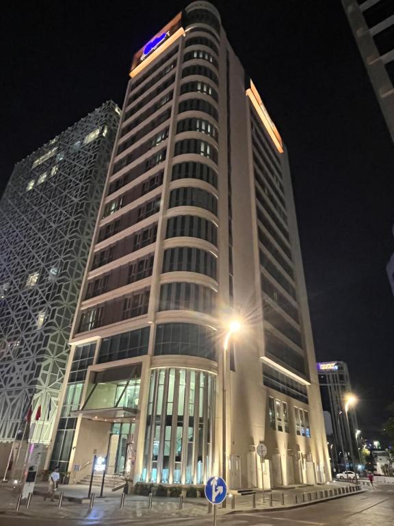 多哈C - Hotel and Suites Doha的前方有街灯的高楼