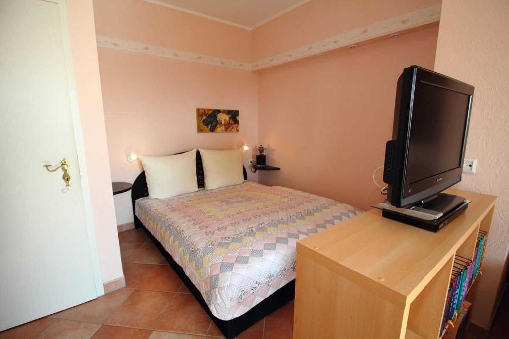 萨斯尼茨Ferienwohnung Gaebel的一间卧室配有一张床和一张书桌上的电视