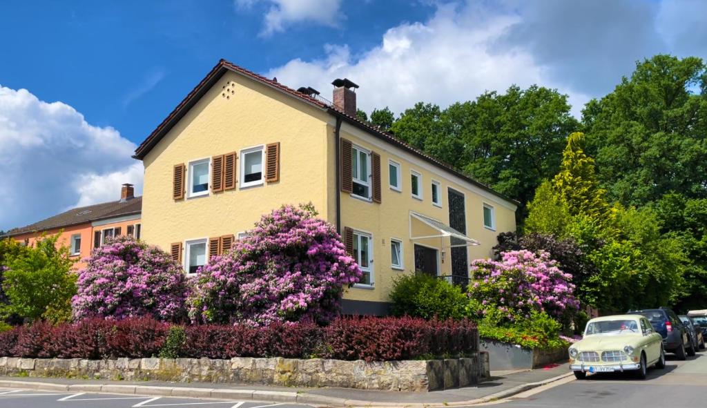 拜罗伊特HEJ Apartments Bayreuth的街上一座黄色房子,花紫色