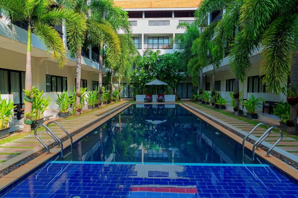 暹粒新河畔酒店的棕榈树建筑庭院中的游泳池