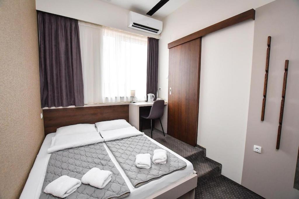 克拉多沃Atrijum Apartments and Rooms的一间卧室配有一张带书桌的床和窗户。