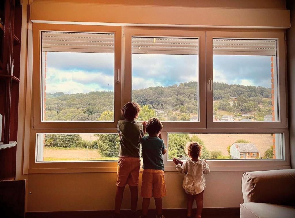 萨里亚López Estación的三个孩子从窗户望出去