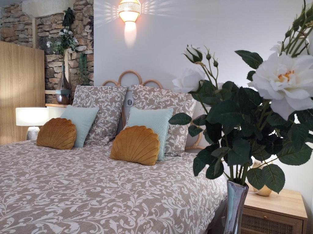 戈尔德La perle de Gordes的一间卧室配有一张带枕头的床和花瓶。