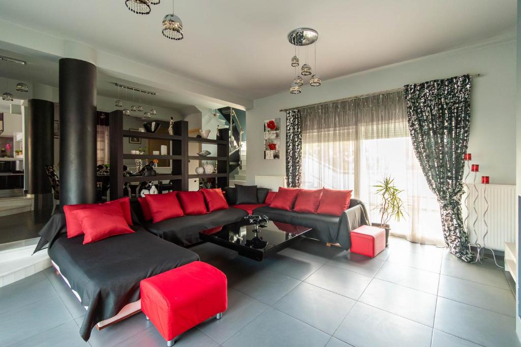 亚历山德鲁波利斯BLACK & WHITE CITY VILLA的客厅配有黑色沙发和红色枕头