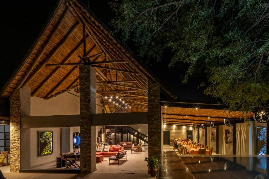 卡萨内Chobe River Lodge的度假村大堂在晚上提供沙发和桌子