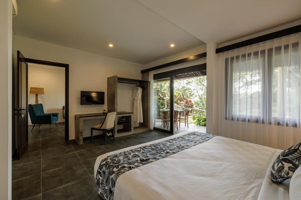 乌布乌布得达利酒店的一间卧室配有一张床、一张书桌和一个窗户。