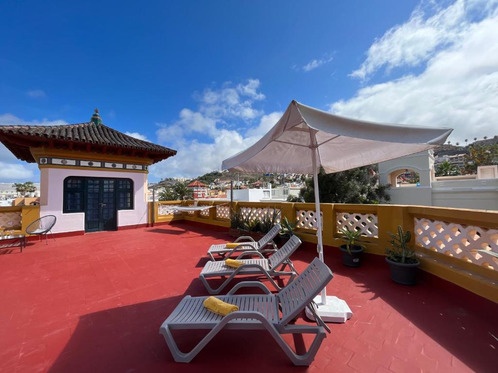 大加那利岛拉斯帕尔马斯CoLiving Villa Brasil的一个带躺椅和遮阳伞的庭院