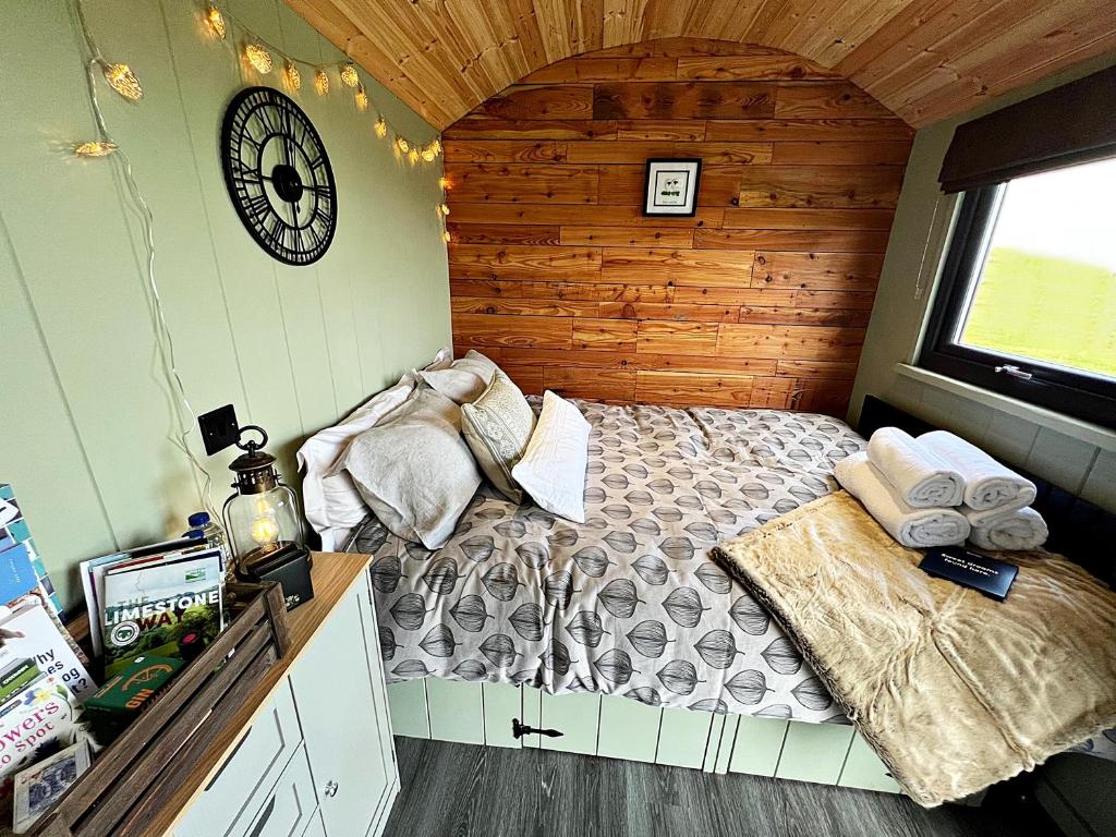 贝克韦尔Luxury Shepherd Hut in the Peak District的卧室配有一张床,墙上挂着一个钟