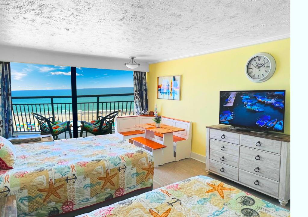 默特尔比奇Ocean Reef- Unique Oceanfront Condo-Free parking - Amazing pools的一间卧室配有一张床、一台电视和一个阳台