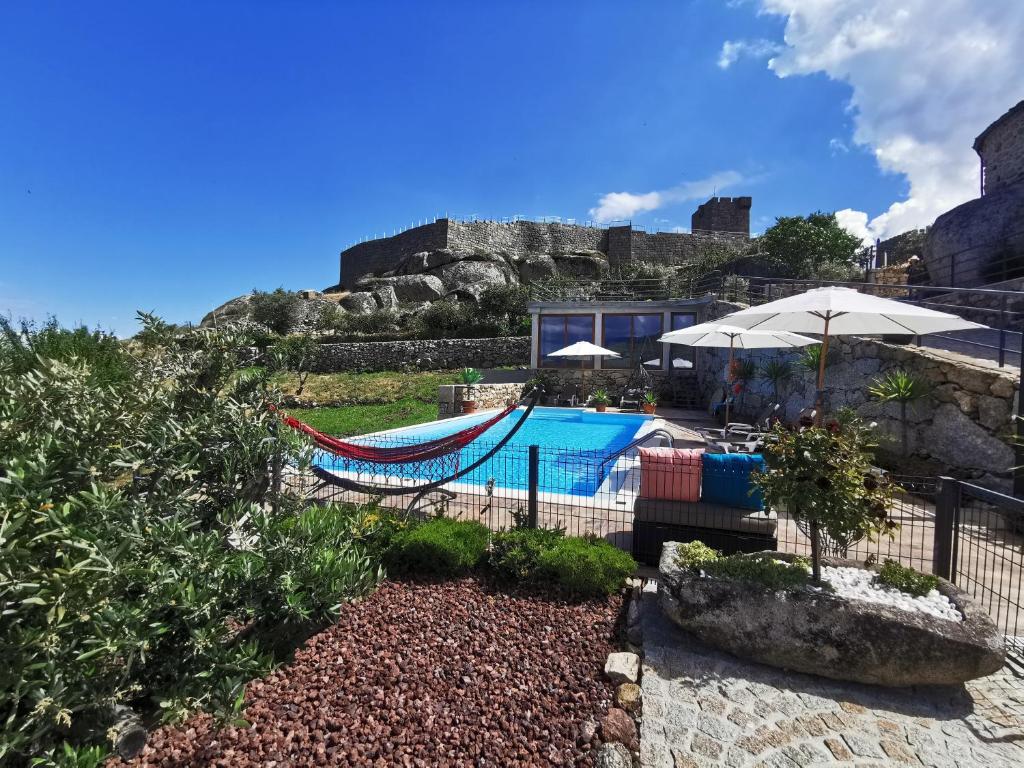 利尼亚雷斯Casa do Penedo Castle House的一个带游泳池和吊床的度假胜地和一座建筑