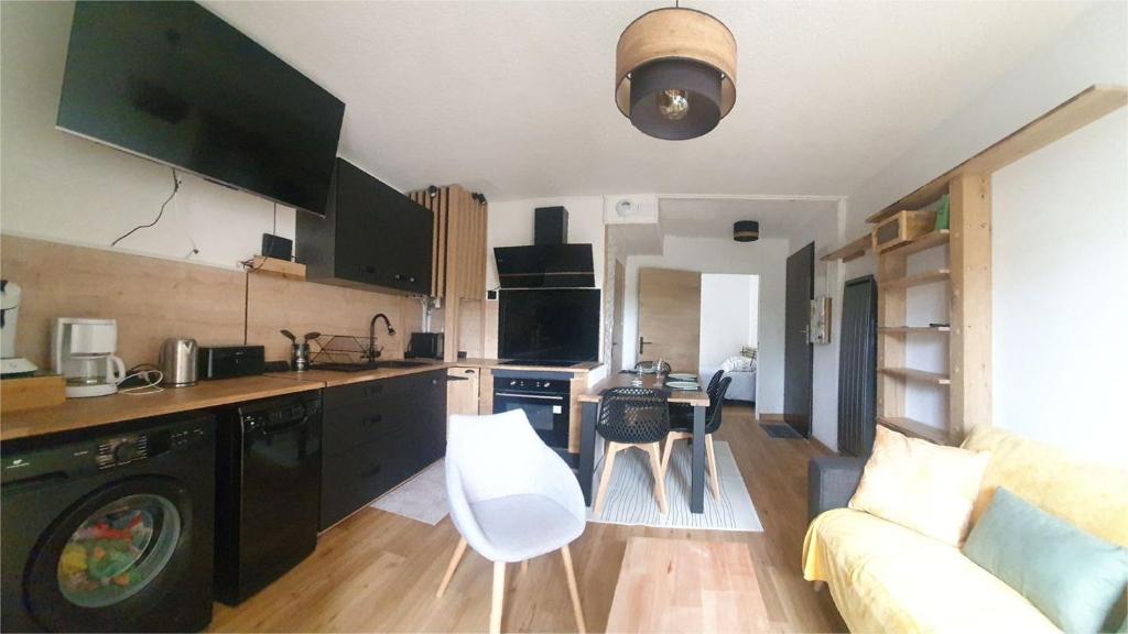 萨尔佐Appartement rez de jardin proche du centre ville de sarzeau的一间带黑色橱柜的厨房和一间带沙发的客厅