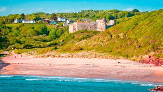 滕比Manorbier Castle Inn Sunset Room的山顶上带城堡的海滩