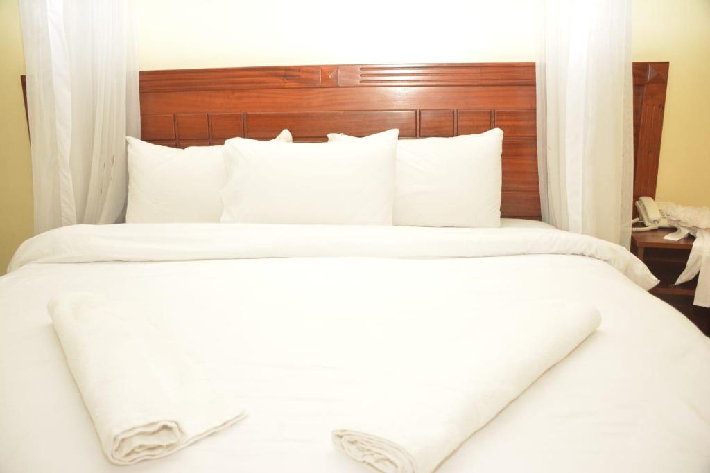 GituraEQUINE RESORT的一间卧室配有两张带白色床单和木制床头板的床。