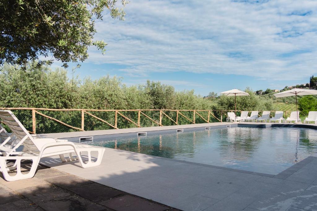 巴尔贝里诺瓦尔德尔萨托雷伊欧洛公寓式酒店的一个带白色椅子和遮阳伞的游泳池