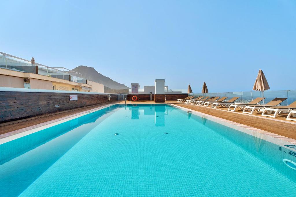 阿德耶Suite Mirador del Galeón的一座蓝色海水和椅子的大型游泳池