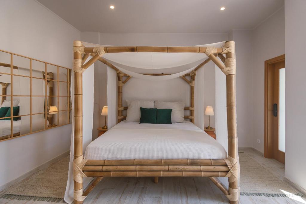 波尔蒂芒Aldeia de Portimão的一间卧室配有一张带绿色枕头的木制天蓬床