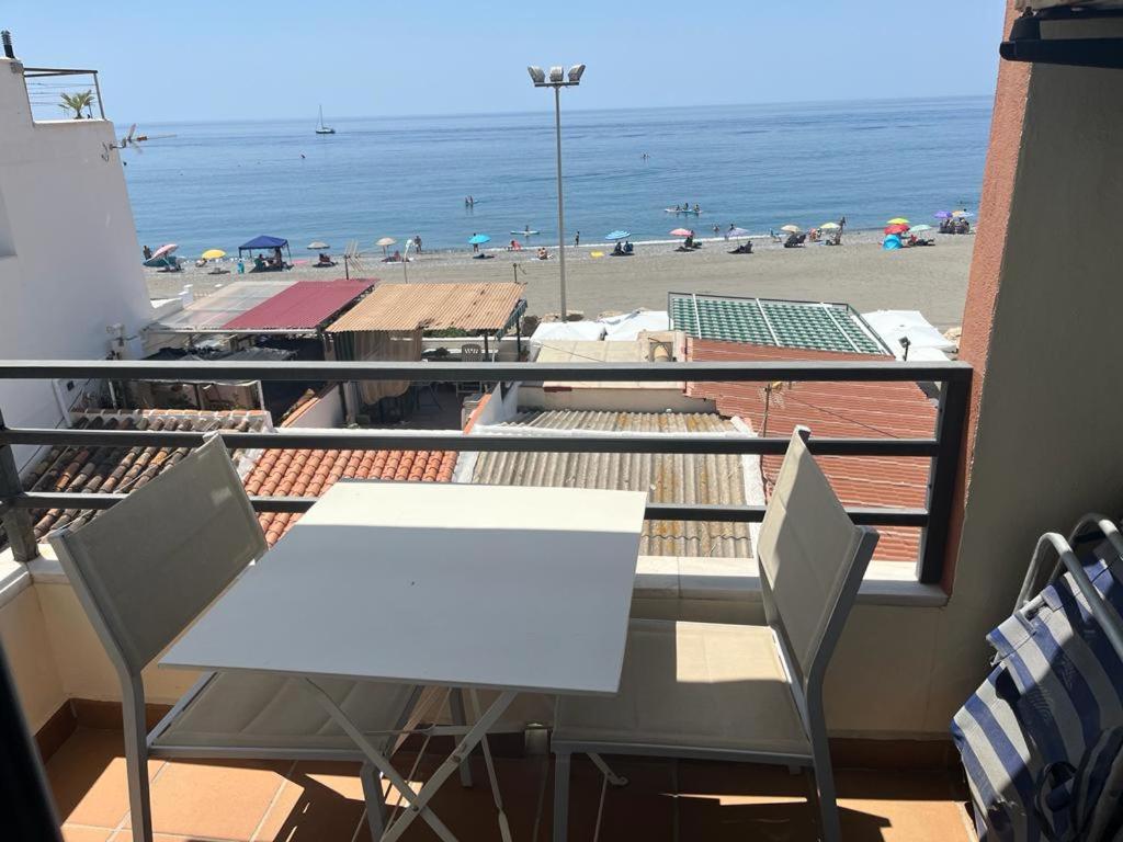 卡莱塔德贝莱斯Maravilloso apartamento en primera linea de playa con vistas al mar en Caleta de Vélez 2 C的海滩阳台的白色桌椅