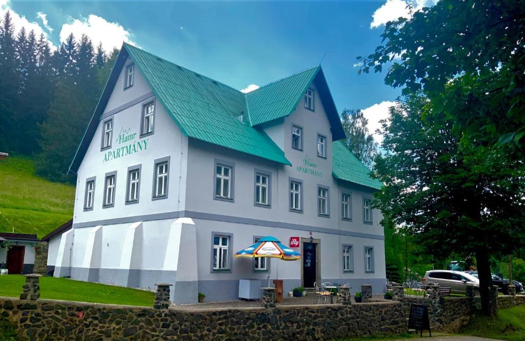 Nové HamryHAMR Apartmány的一座白色的大建筑,设有绿色屋顶