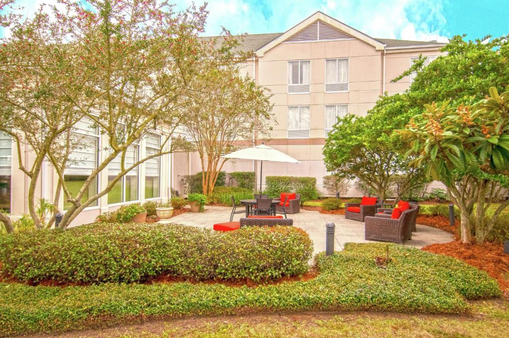 肯纳新奥尔良机场希尔顿花园酒店的一座带家具和树木的庭院的建筑