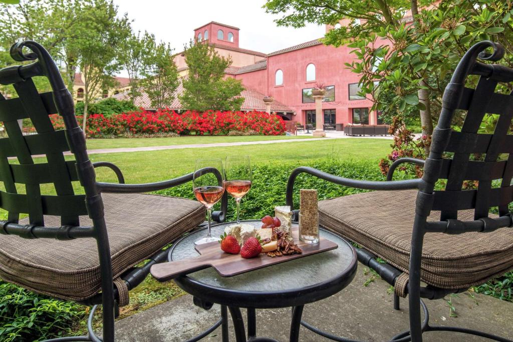 罗内特公园索诺马酒乡希尔顿逸林酒店的一张桌子、两把椅子和一盘水果及酒杯