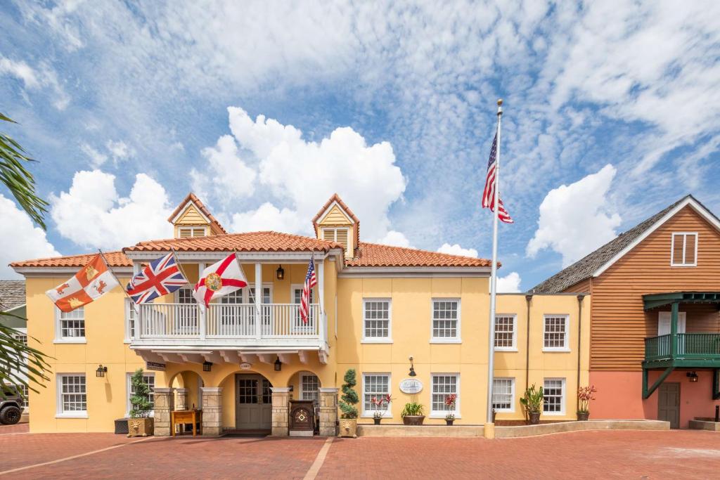 圣奥古斯丁希尔顿圣奥古斯丁历史海湾酒店的黄色的建筑,带有带有国旗的阳台