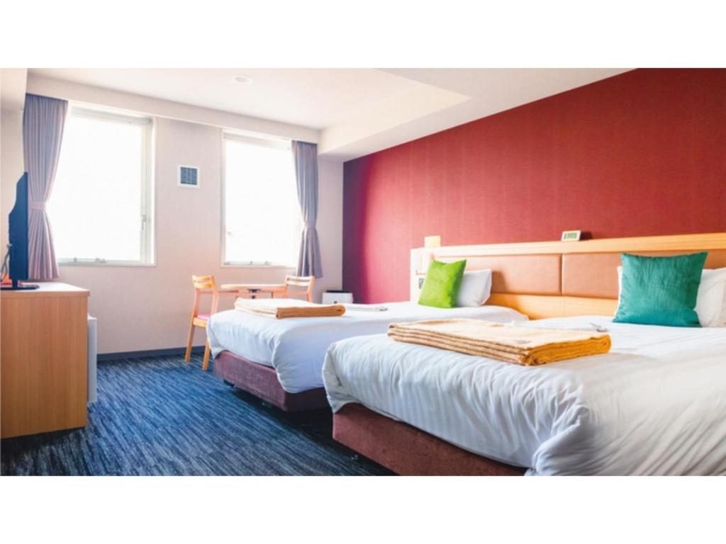 姶良市AIRAIKU HOTEL Kagoshima - Vacation STAY 17451v的红色墙壁的酒店客房内的两张床