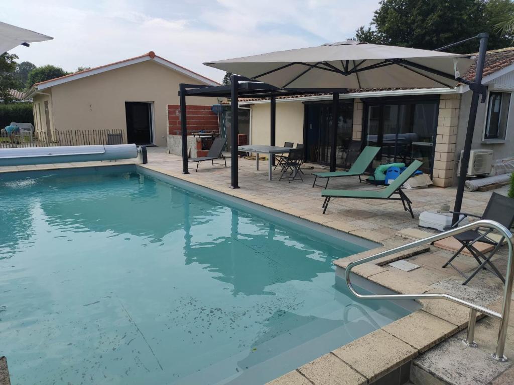 拉特斯特德布赫2 Maisons de 3 et 2 chambres avec grande piscine commune的一个带遮阳伞和椅子及桌子的游泳池