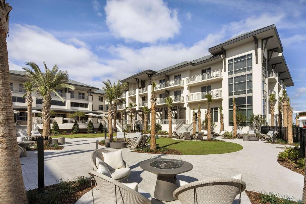 圣奥古斯丁海滩Embassy Suites St Augustine Beach Oceanfront Resort的建筑前的庭院配有桌椅