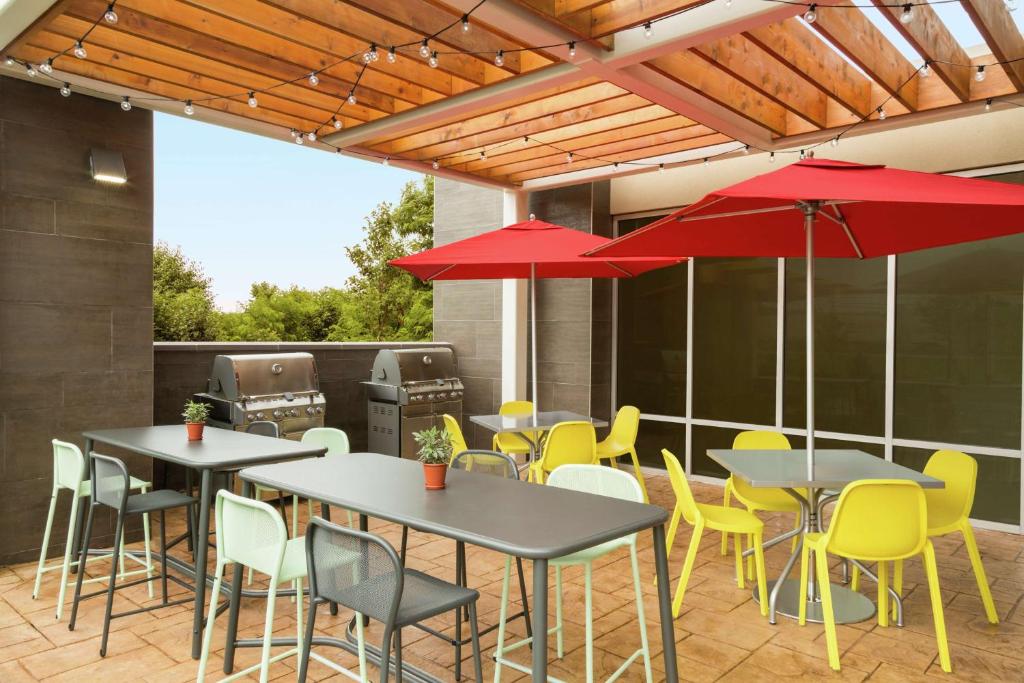 弗雷德里克Home2 Suites By Hilton Frederick的一个带桌椅和红色遮阳伞的庭院