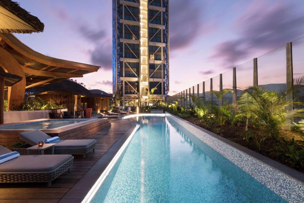 莫尔兹比港Hilton Port Moresby Hotel & Residences的一座带躺椅的游泳池和一座建筑