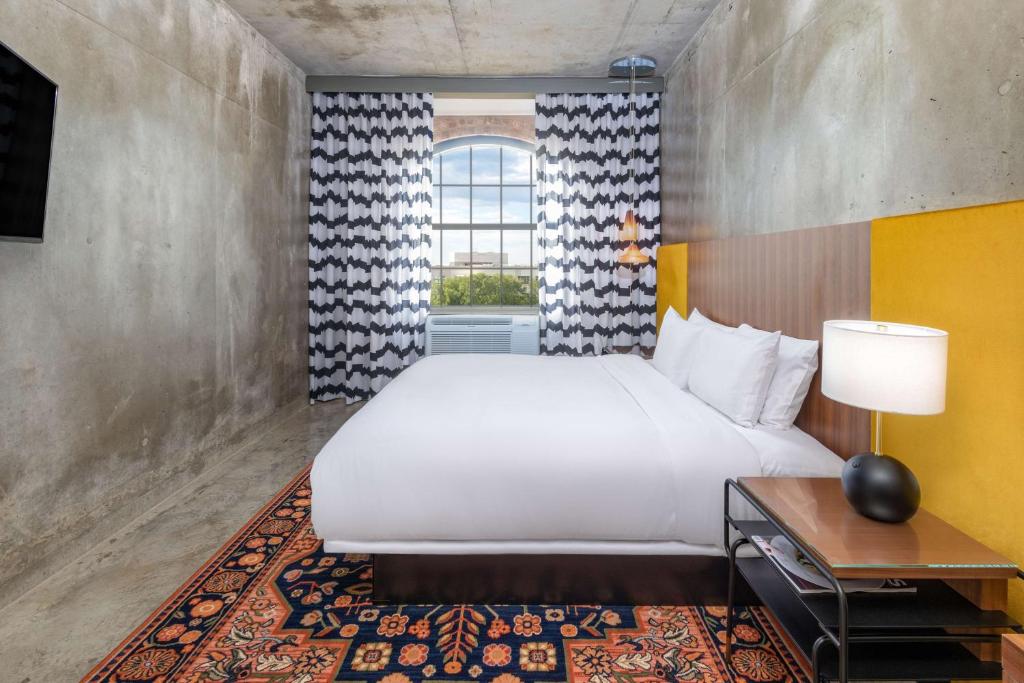 欧文NYLO Las Colinas Hotel, Tapestry Collection by Hilton的一间卧室设有一张大床和一个窗户。