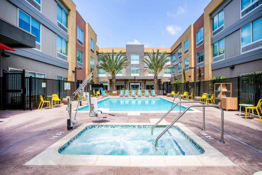 卡尔斯巴德Home2 Suites By Hilton Carlsbad, Ca的一座带椅子的游泳池以及一座建筑