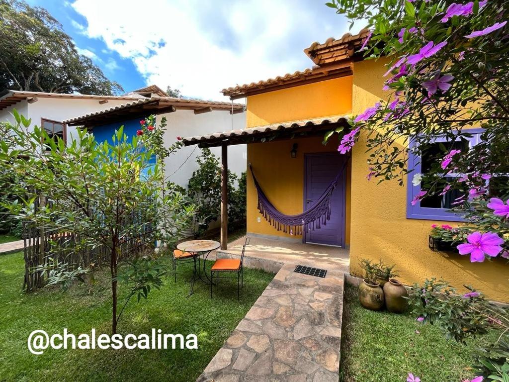 伦索伊斯Chalés Calima的黄色的房子,有紫色的门和院子