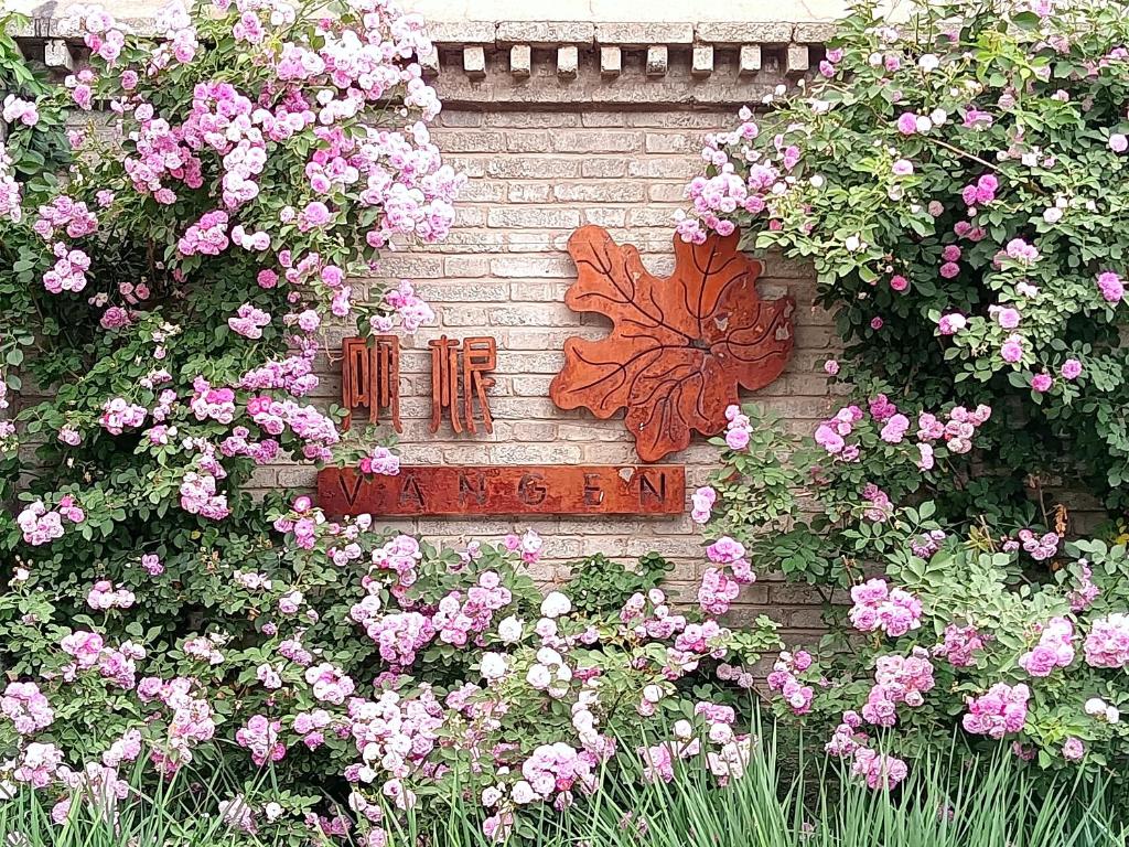 密云Vangen Hotel的砖墙,上面有粉红色的花和蝴蝶