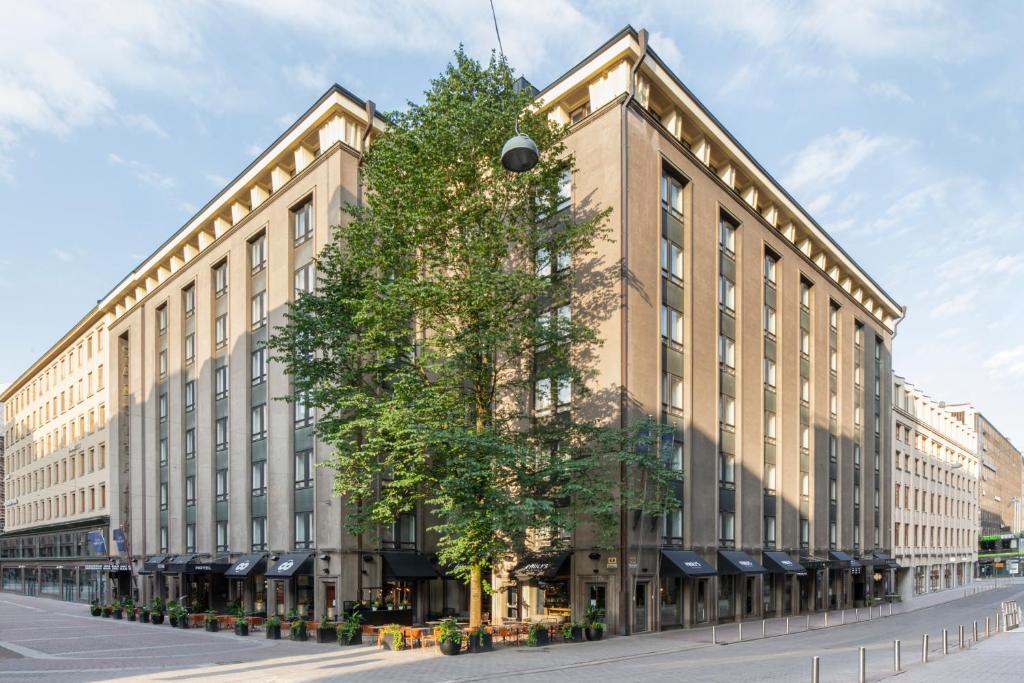 赫尔辛基Solo Sokos Hotel Helsinki的前面有一棵树的大建筑