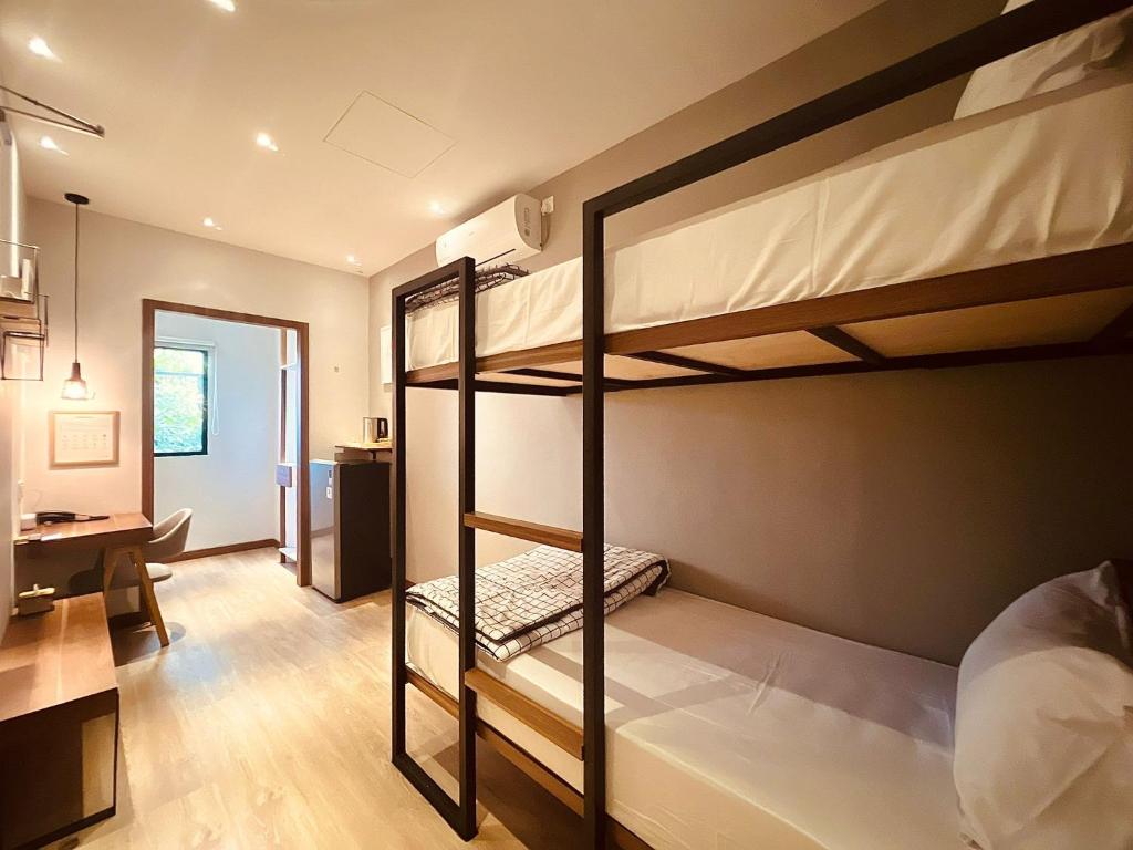 巴淡岛中心oxy suites 2-06 at Shop House Meisterstadt Pollux Habibie的客房设有两张双层床和一张书桌。