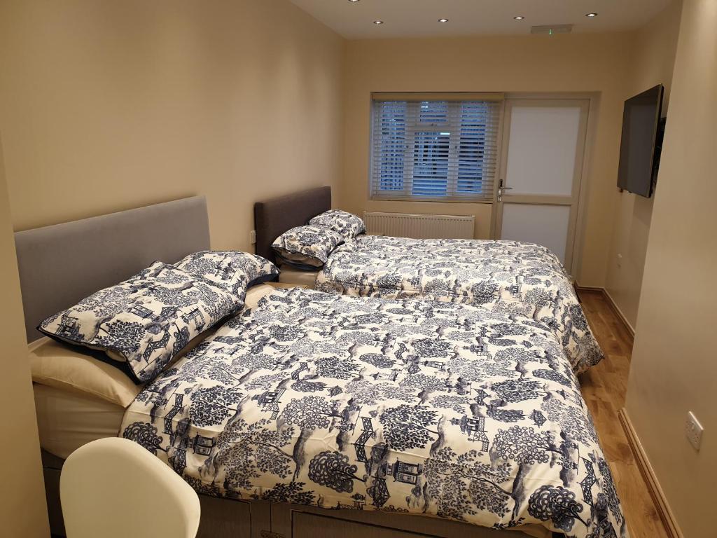 依尔福London Luxury Apartments 3 Bedroom Sleeps 8 with 3 Bathrooms 4 mins walk to tube free parking的一间卧室设有两张床、一个窗口和椅子