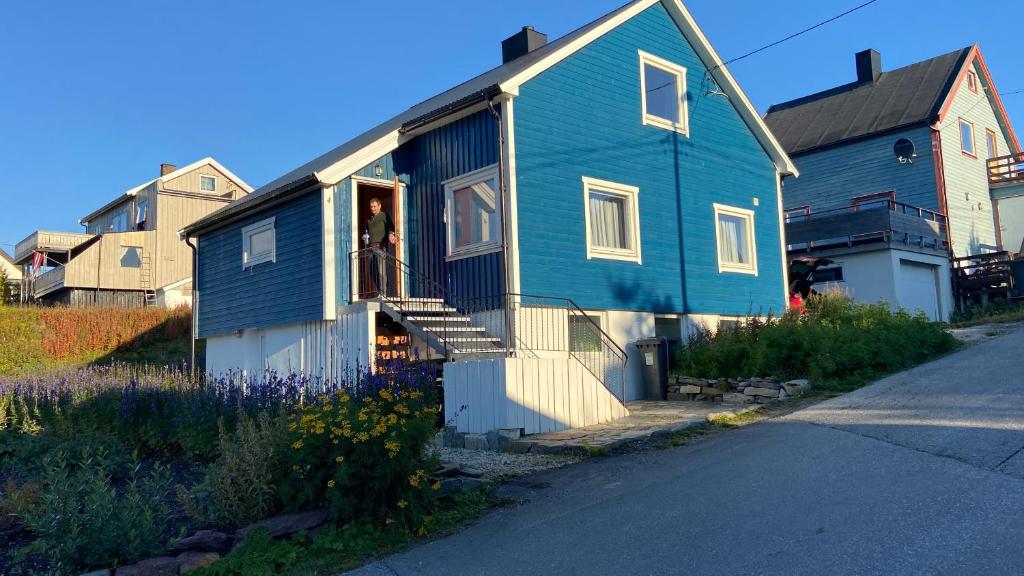 梅哈姆The Blue House at The End Of The World II的一座蓝色的房子,一个人站在门上