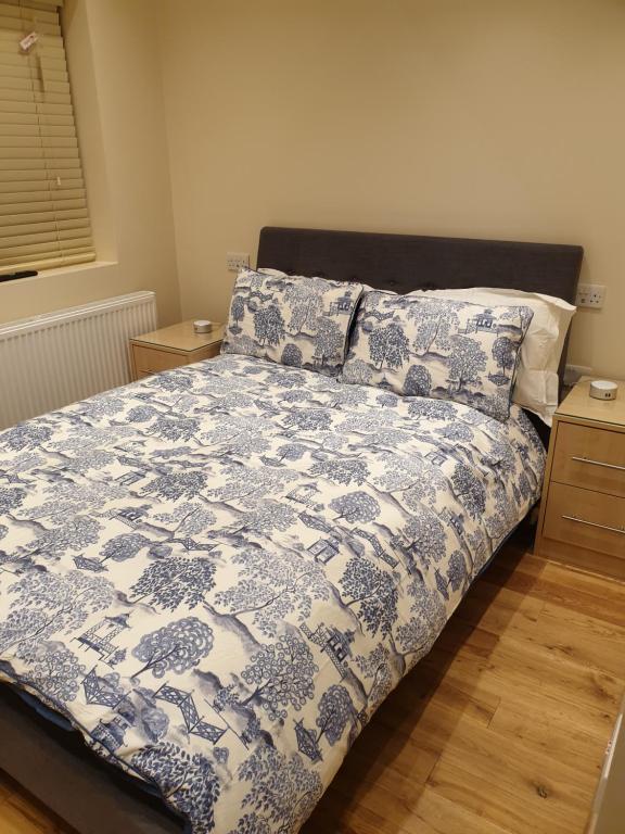 依尔福London Luxury Apartments 3 Bedroom Sleeps 8 with 3 Bathrooms 5 mins Walk to tube station free parking的一间卧室配有一张带蓝色和白色棉被的床