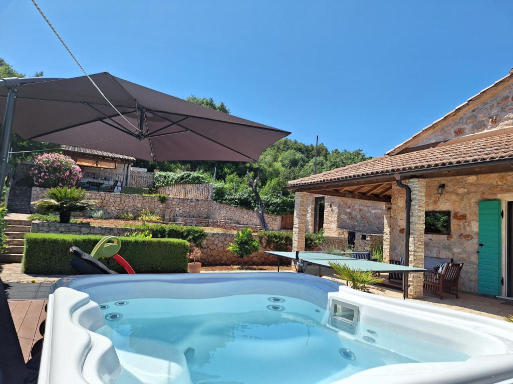 兹曼Villa Aurelia的庭院内的热水浴池,配有遮阳伞