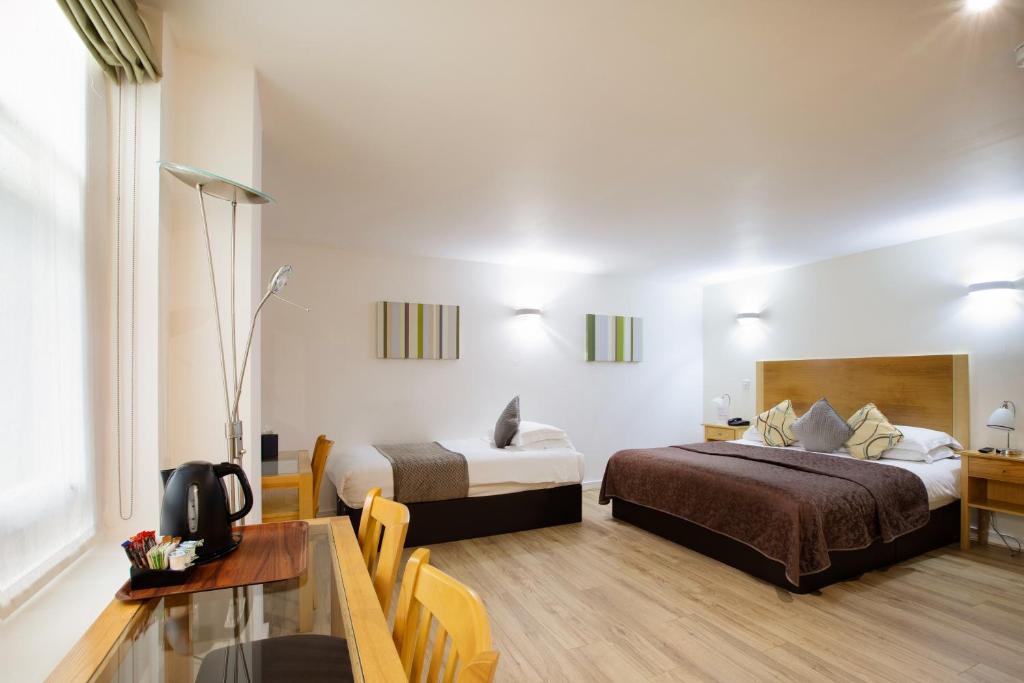 伦敦克利夫兰酒店的酒店客房设有两张床和一张桌子。