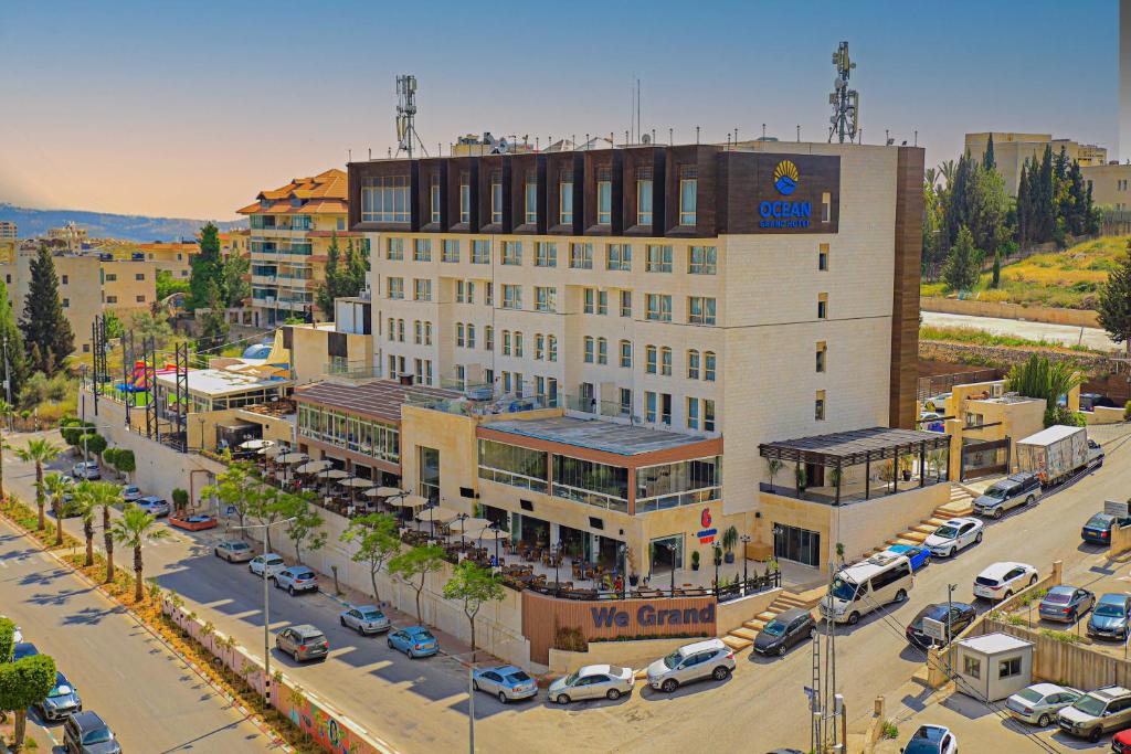 拉马拉Ocean Grand Hotel - Ramallah的停车场内一座大型建筑,有停放的汽车