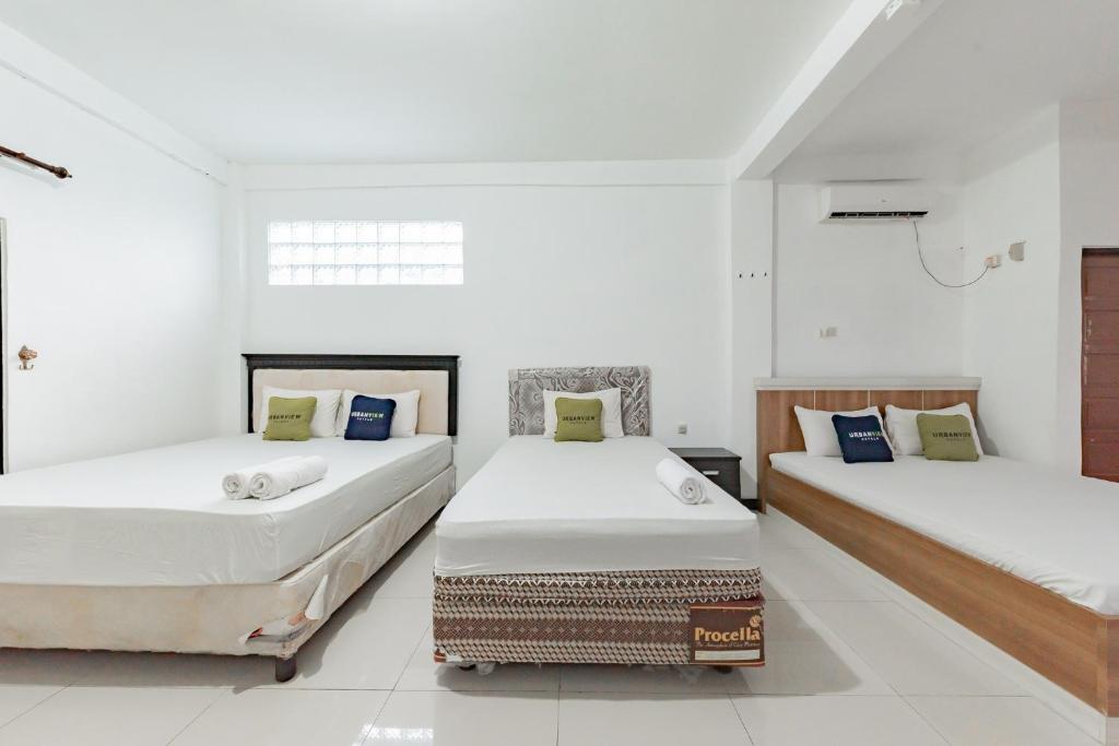 MartapuraUrbanview Hotel 99 Syariah Banjarbaru by RedDoorz的白色墙壁客房的两张床