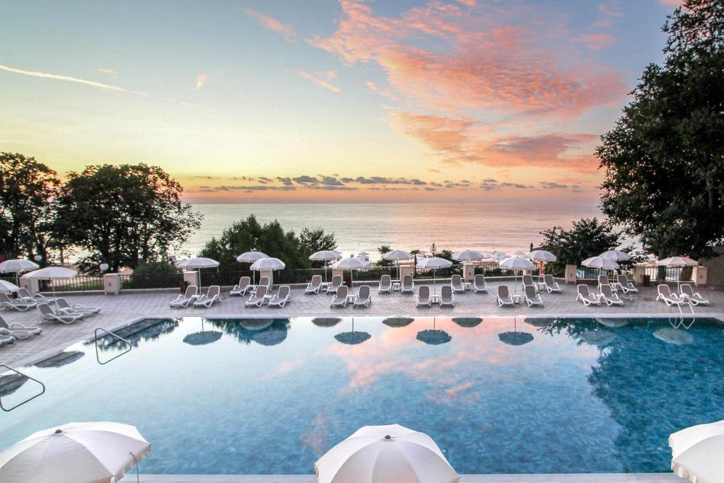 金沙GRIFID Vistamar Hotel - 24 Hours Ultra All inclusive & Private Beach的一个带椅子和遮阳伞的游泳池以及大海