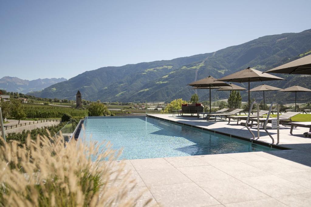 纳图尔诺Feldhof DolceVita Resort的一个带桌子和遮阳伞的游泳池以及山脉
