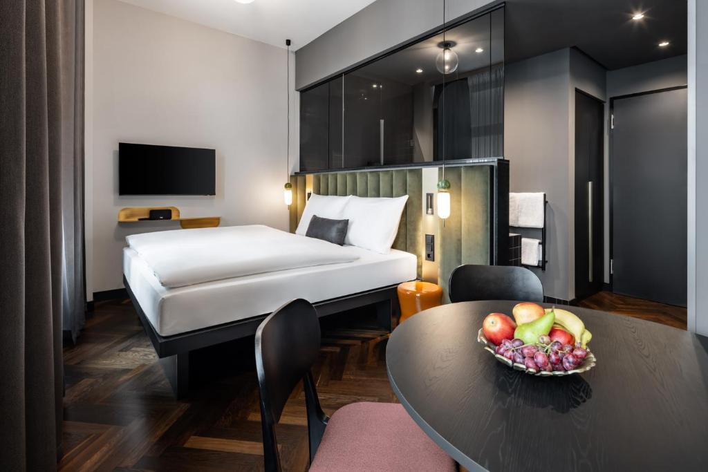 莱比锡AMANO Home Leipzig的酒店客房,配有一张床和一碗水果放在桌子上